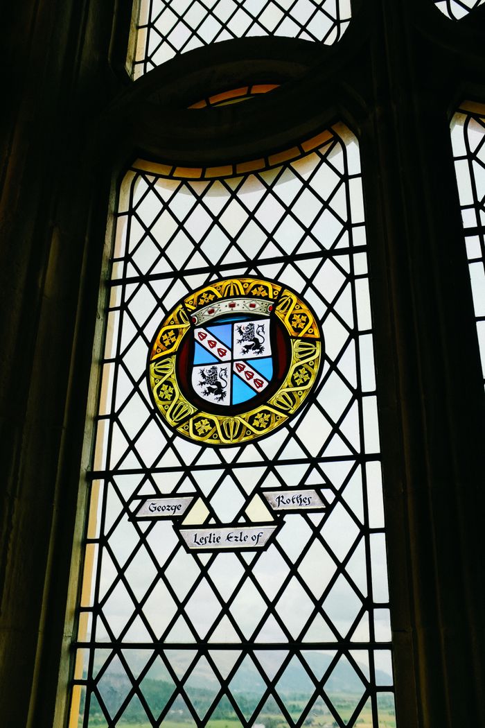 Detailed stained glass window featuring a historical coat of arms in vibrant colors.