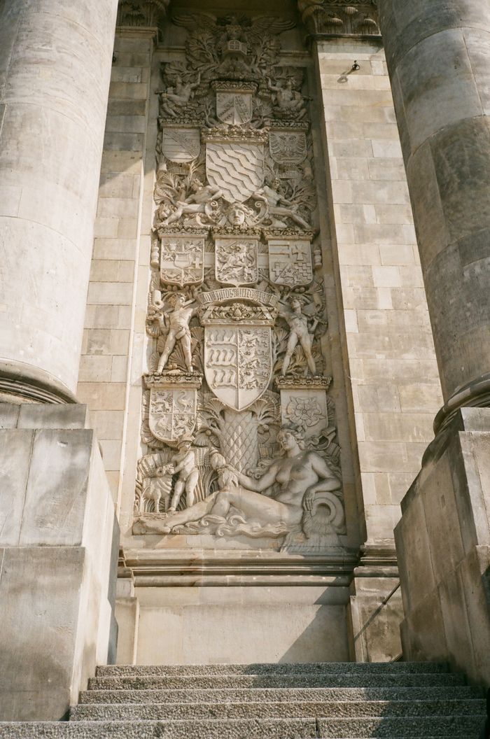 Low-angle view of an ornate stone carving on a historic building facade, highlighting classical architecture.